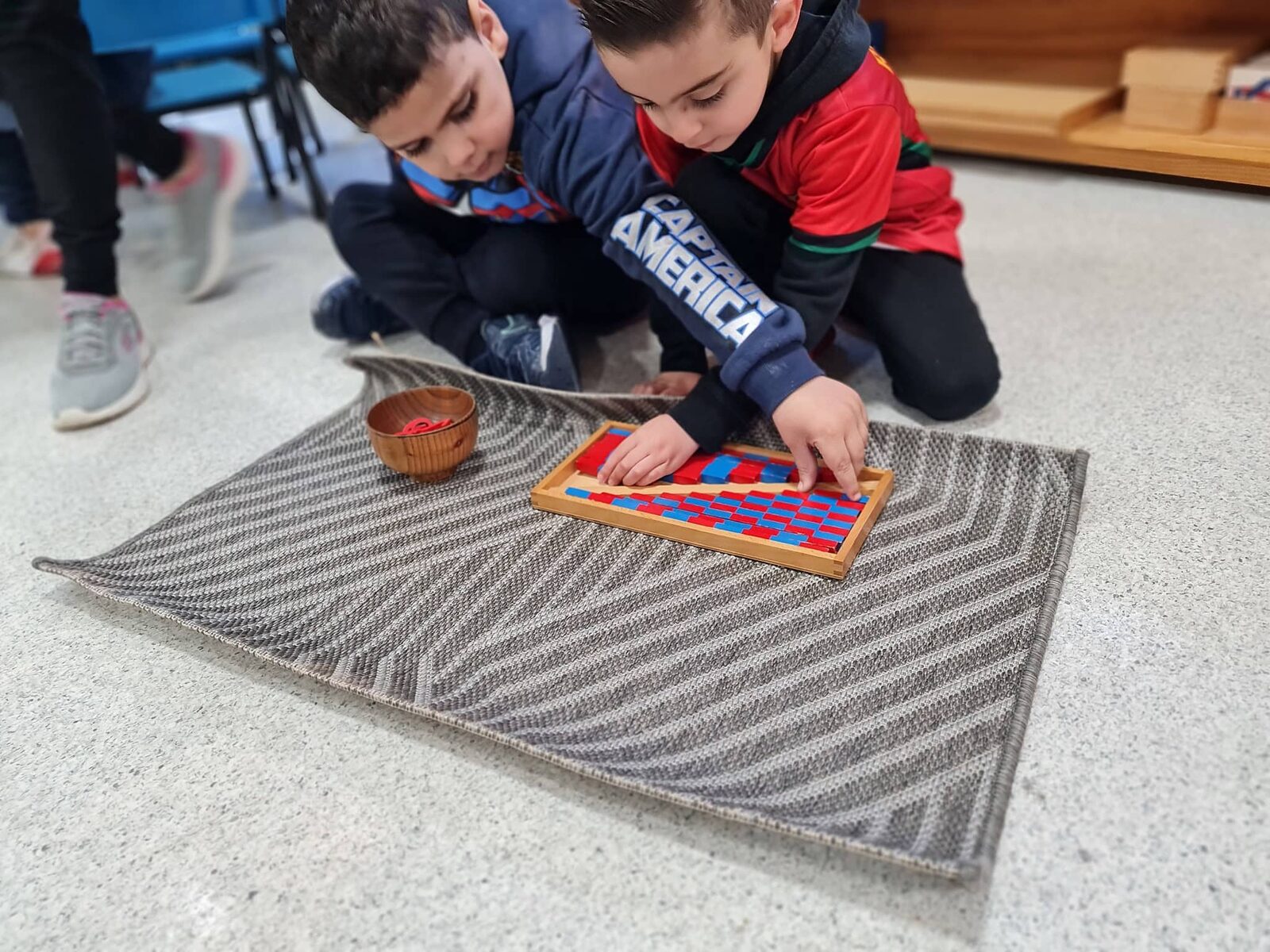 Two children working together with Montessori bead and rod materials